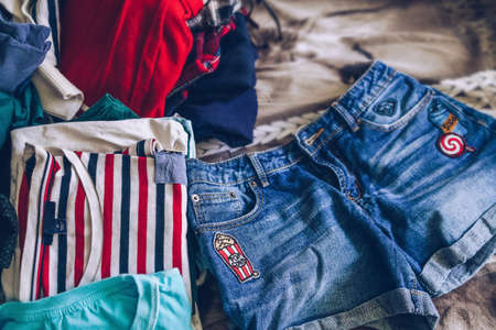 choosing clothes concept with messy pile on background and jeans shorts in frontの写真素材