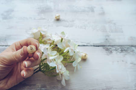 woman holding decorated with golden wire and loop white bead with hydrangea and wooden background