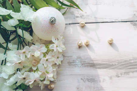 top view of white chistmas ball in white flowers with golden beads decor on wooden backgroundの写真素材