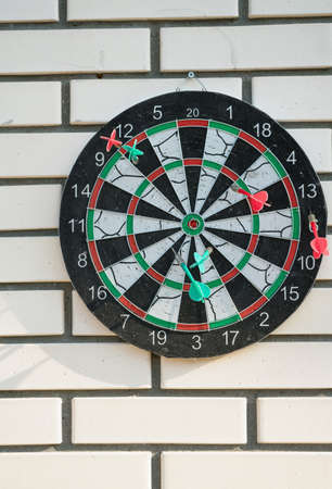 darts game on white brick outdoor wall with scores and slips