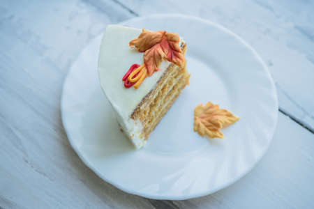 slice of cake decorated with autumn leaves on white plate and wooden background