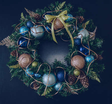 festive handmade christmas wreath decorated with blue beige and green christmas decor on dark background with space for textの写真素材