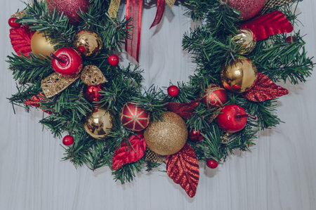 part view of handmade christmas wreath with red and golden decor on light wooden backgroundの写真素材