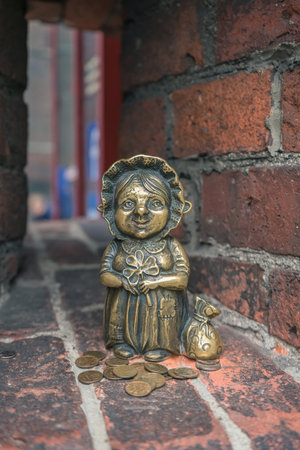 Kaliningrad, Russia - may 15, 2021: cute modern sculpture of Grandmother Homlin on brick wall of amber museum with coins beside herのeditorial素材