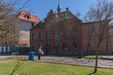 Zelenogradsk, Russia - may 11, 2021: cityscape on sunny spring day with man going to use trash can
