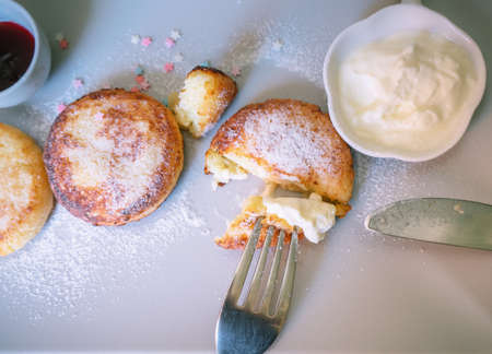 eating freshly made cottage cheese pancakes with sour cream and berry jam