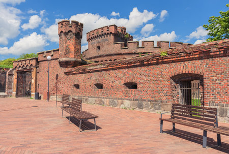 exterior and resting area with benches in front of old fortifications of on sunny spring day