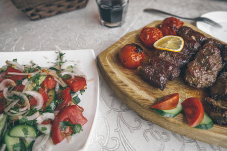 view from above on marinated meat and vegetables cooked and served with fresh salad on wooden boardの写真素材