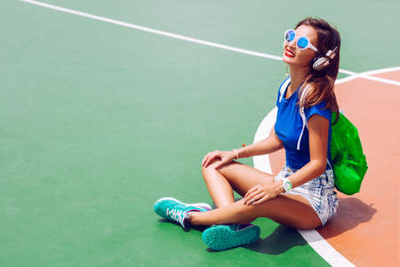 Young sexy sportive tan woman siting in fashion sportive outfit, neon backpack and mirrored...