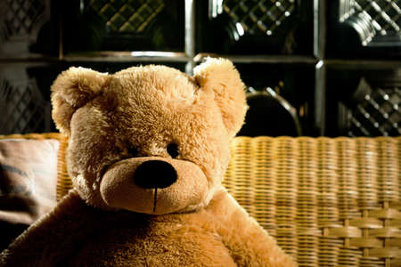 Teddy bear sitting by a ceramic wood stove.の写真素材