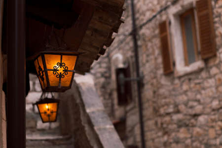 Lanterns hanging in an alleyway among old stone buildingsの写真素材