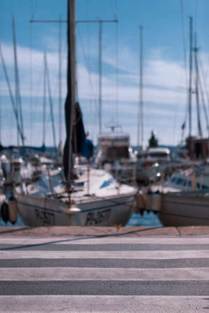Zebra crossing leading to sailing boats docked in marinaの写真素材
