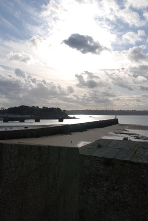 view of the harbour at low tide with cloudy sky in the backgroundの写真素材