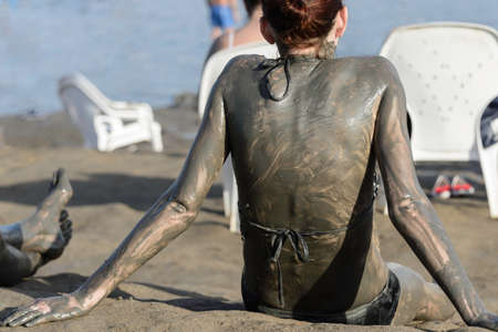 Young woman enjoying the natural mineral mud sourced from Dead sea, Israel. Body care treatment.