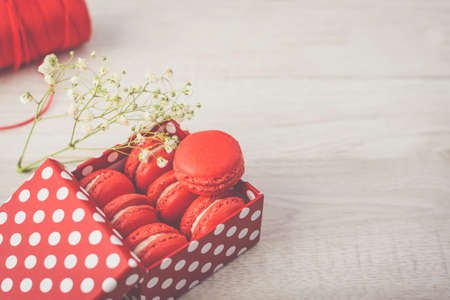 Stylish red dots box with tasty macarons on wooden background. Minimalist concept of style and french chic, copy space and selective focus.の写真素材