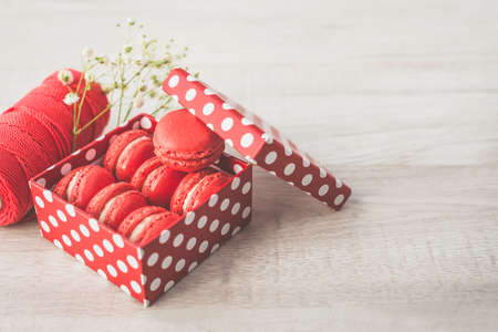 Stylish red dots box with tasty macarons on wooden background. Minimalist concept of style and french chic, copy space and selective focus.の写真素材