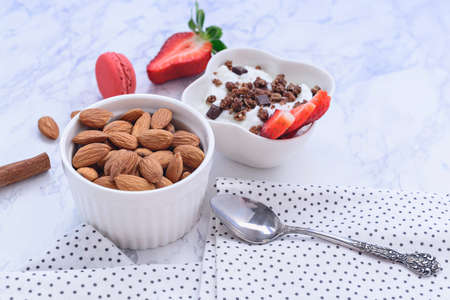 Stylishly decorated and healthy breakfast - strawberries, yoghurt with granola and almonds on a...
