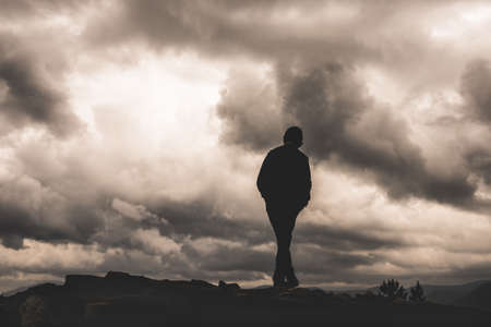 Boy silhouette on the background of clouds and darkness. A sense of loneliness, freedom, despair or...
