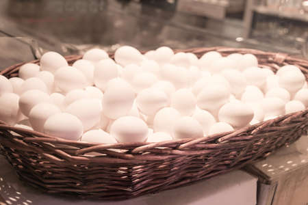 White chicken eggs in large wicker basket., close up.の写真素材