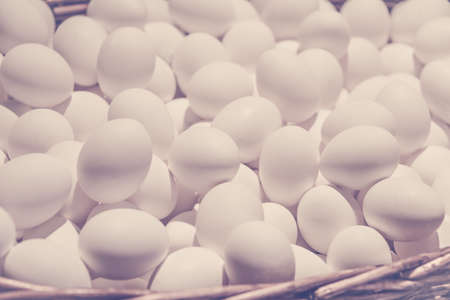 White chicken eggs in large wicker basket., close up.