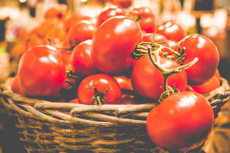 Rustic basket of fresh organic tomatoes on dark background in farmer market.の写真素材