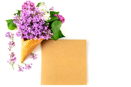 Flowers composition. Lilac in waffle cone and postcard of kraft paper on white background. Flat lay, top view, copy space. Concept of proposal, gratitude, tenderness and love.の写真素材