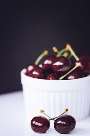 Fresh ripe cherries in ceramic bowl. Isolated on white background, close up. Healthy food concept.の写真素材
