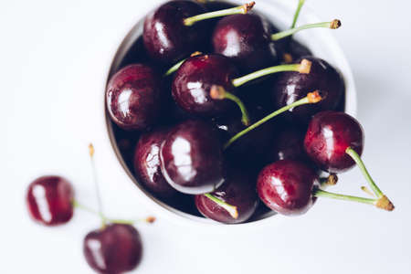 Fresh ripe cherries in ceramic bowl. Isolated on white background, close up. Healthy food concept.