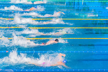 Young swimmers in outdoor swimming pool during competition. Health and fitness lifestyle concept with kids.の写真素材