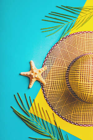 Summer composition. Tropical palm leaves, straw beach hat, starfish on pastel blue and yellow background. Concept summer trip. Flat lay, top view, copy space.の写真素材
