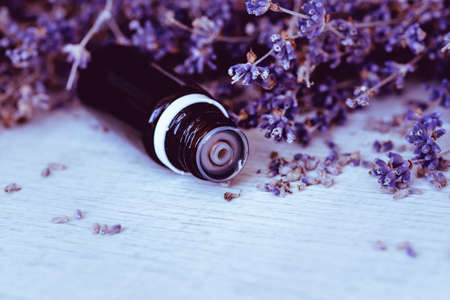 Herbal essential oil and lavender flowers on wooden background. Close up and copy spaceの写真素材