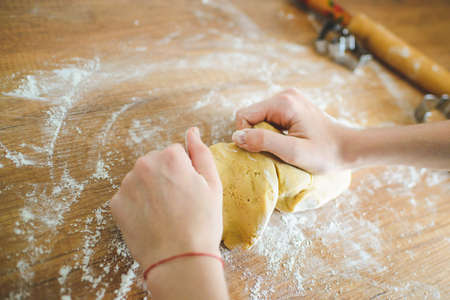 Christmas cookies preparation. Cookies cutter, dough for cookies and rolling pin on the kitchen table. Homemade treats. Selective focus.の写真素材