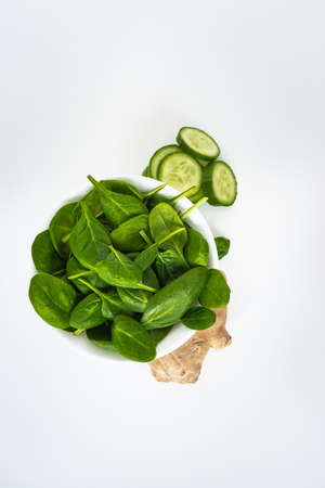 Fresh green leaves spinach, slices of cucumber and ginger isolated on a white background. Copy space for text. Healthy and detox conceptの写真素材