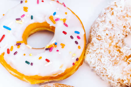 Assorted multicolored donuts in a bakery box with chocolate frosted, glazed and sprinkles donuts....