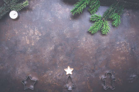 Christmas holiday background with cookie cutters, evergreen fir branch on vintage style dark...
