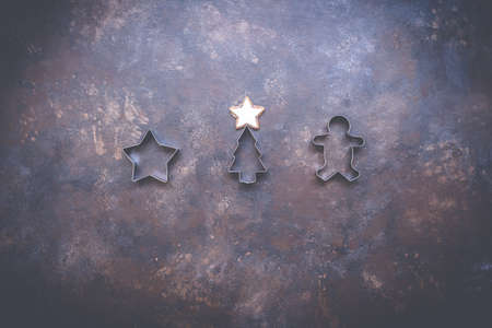 Christmas holiday background with cookie cutters on vintage style dark background. Concept of holiday coziness, top view, flat lay, copy space.の写真素材