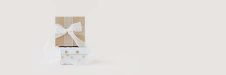Beige and dotted gift boxes with white silk ribbon on pastel background. Elegant present banner....