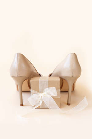 Classic beige women high heel shoes and gift box on pastel background. Minimal female background, banner. Fashion blog and sale concept.の写真素材