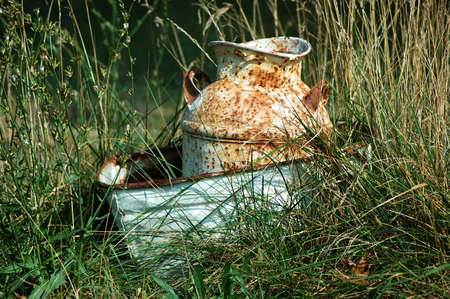 Rusty milk jug sitting in an old dishpan out in a farmer's field in Kentucky USA.の写真素材