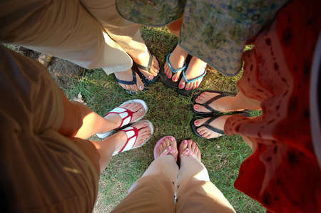 Summer Feet - A group of teen girlfriends stand in a huddle showing their painted toe nails and summer sandals.の写真素材
