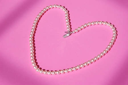 Vintage Pearls - A string of antique pearls with a diamond clasp lays in a heartの写真素材