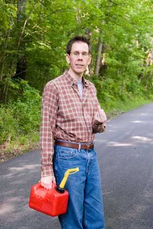 Upset man holding a gas can on a country road, flipping the bird.の写真素材