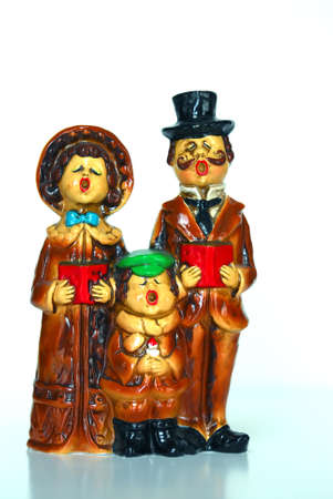 Vintage Christmas Carolers from the early 1900s.  Man, woman and child holding songbooks and singing. White background and reflection at bottom.の写真素材