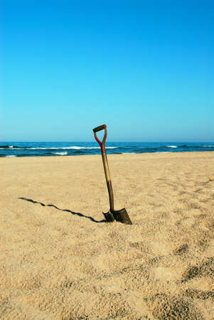 A shovel in the sand at Lake Michigan on the beach in summertime.の写真素材