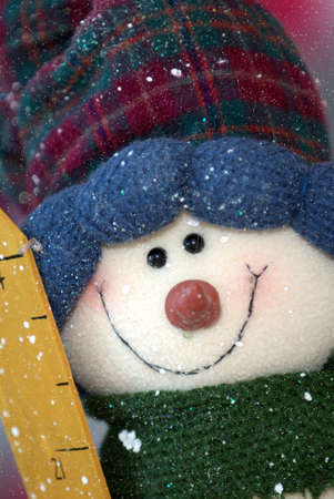 A snowman dressed in warm winter clothing as it snows.の写真素材