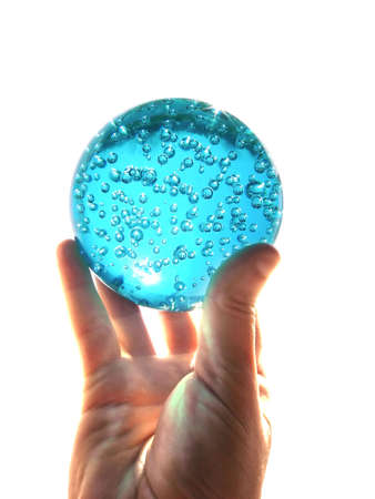 A hand holding a glass ball - conceptual relation with water ressources or divinationの写真素材