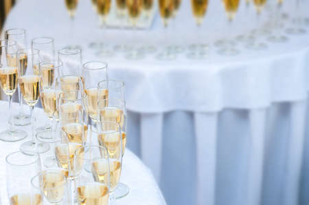 A lot of wine glasses with a champagne or white wine on the round table. Alcohol backgroundの写真素材