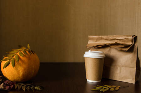 Autumn business lunch, still life with pumpkin and foliage. Dark brown textured background with copy spaceの写真素材
