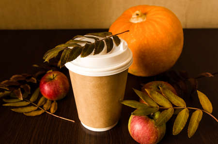 Coffee cup and pumpkin, still life with foliage on black woodの写真素材