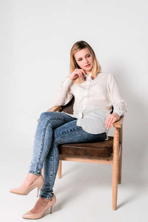 Young beautiful woman sits on a chair thought about somethingの写真素材